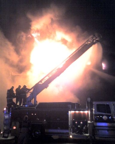 Large fire ball rises behind a fire truck.